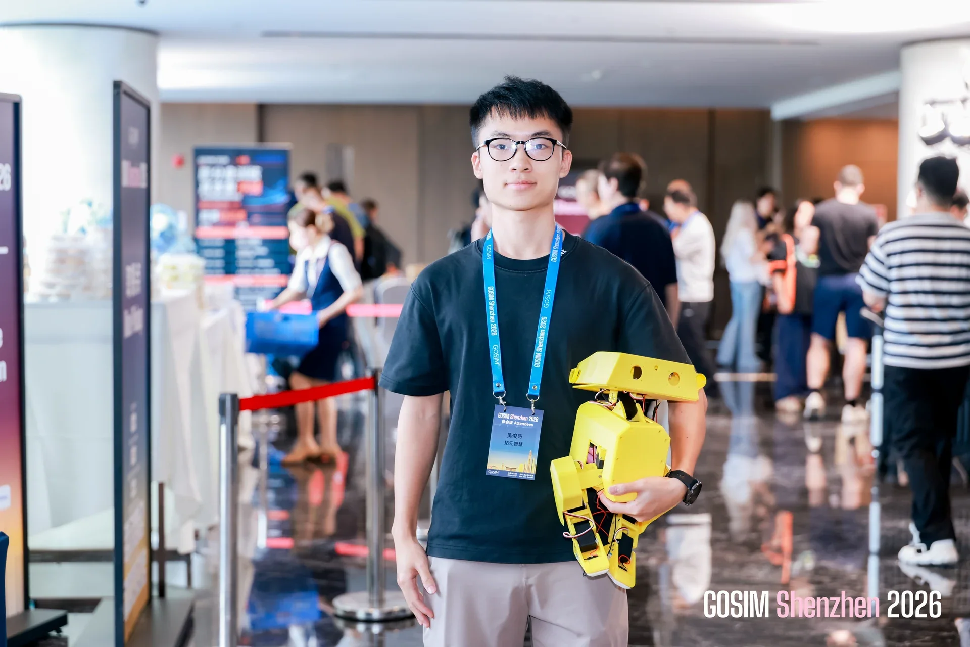 A conference participant holding a yellow robot in the exhibition area